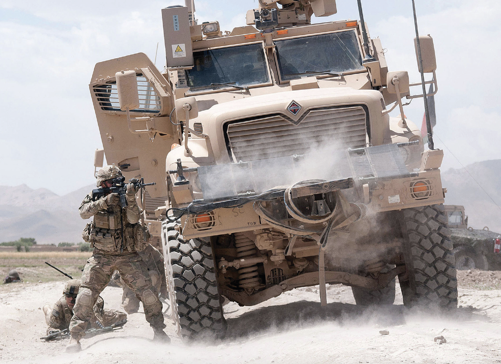 U.S. Army paratrooper with 82nd Airborne Division’s 1st Brigade Combat Team, shielded by Mine Resistant Ambush Protected vehicle, fires his M4 carbine at insurgents during firefight, June 30, 2012, in Ghazni Province, Afghanistan (U.S. Army/Michael J. MacLeod)
